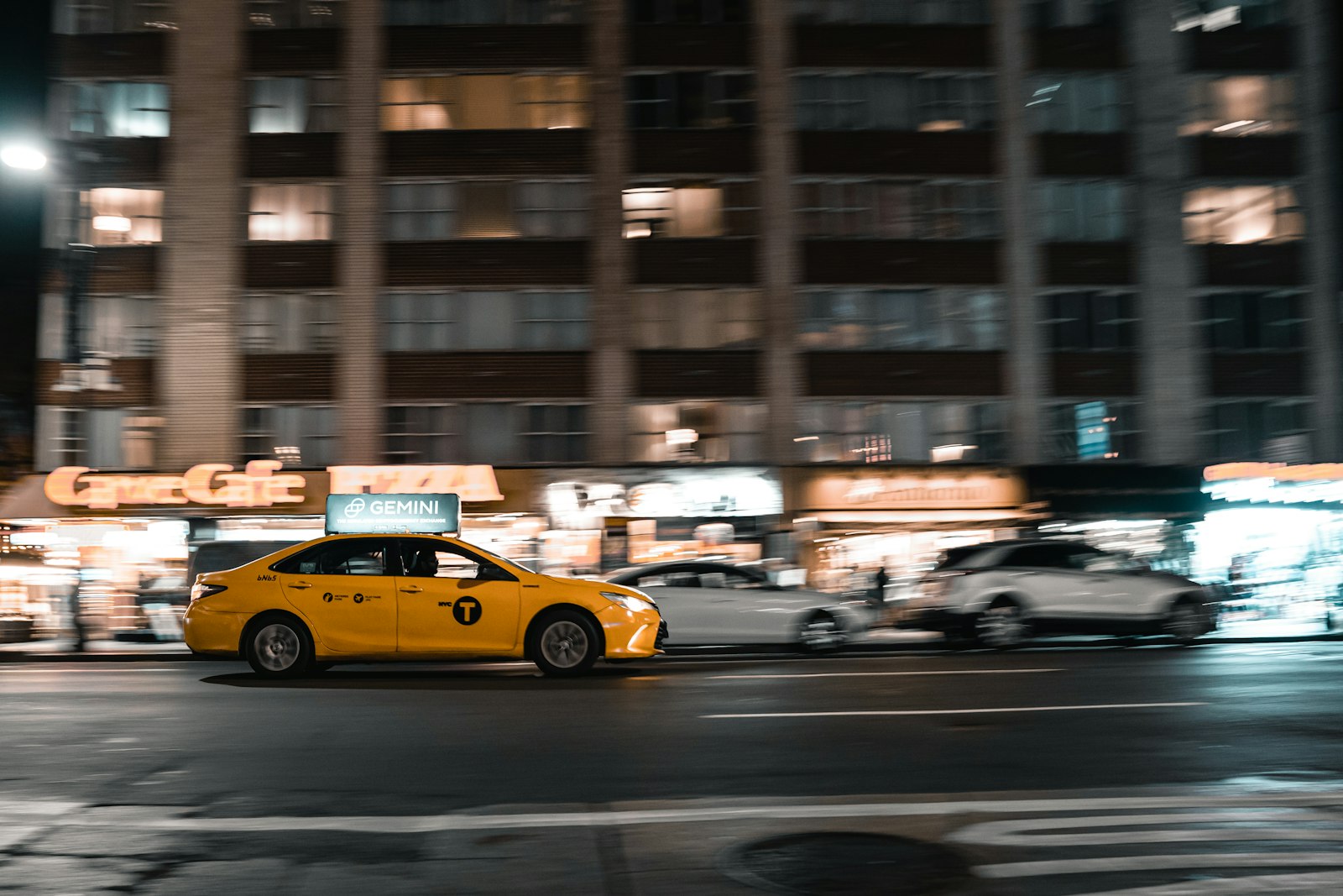 Taxi with a rooftop advertising display driving through a city at night